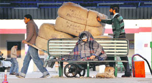 A passenger wraps himself in a blanket as he awaits a train at the Ludhiana railway station on a chilly day.