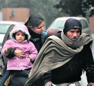 A woman and her child all wrapped up in warm clothes take a rickshaw ride on a cold Sunday morning in Ludhiana.
