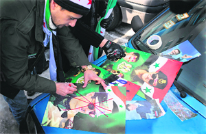 A Syrian immigrant crosses out a portrait of President Bashar al-Assad during a rally against his regime in Sofia on Sunday.