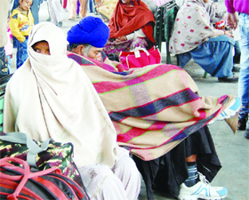 People brave the chill at the railway station in Amritsar on Monday. 
