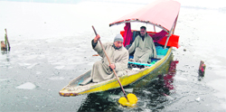 A man uses an oar to break the frozen surface of the Dal Lake in Srinagar on Monday. Temperatures remained below freezing point in the Valley.