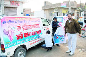 NGO activists paste posters on a van educating people on the power of the ballot