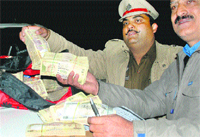 Members of a surveillance team show the wads of currency in Mohali 