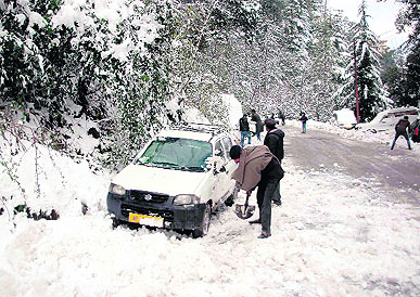 A man clears the snow with a shovel after his vehicle got stuck in Shimla on Tuesday.