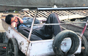 A man takes a nap on a sunny day outside the main bus stand in Jammu.