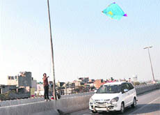 Unmindful of the danger, a boy flies a kite on a flyover leading to the Jalandhar bypass in Ludhiana. 