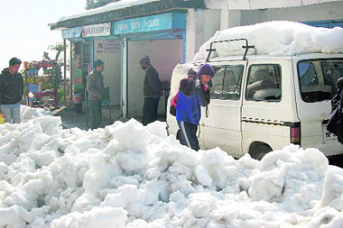 A youngster carries goods to his home on a snow-covered road at Nandi village near McLeodganj 