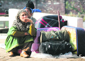 Kashmir-bound stranded passengers rest at the bus station in Jammu on Thursday. 