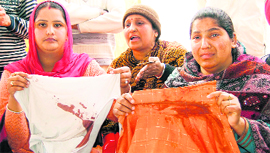 Satinder Kaur shows the blood-stained clothes of her husband Sahib Singh in Amritsar.