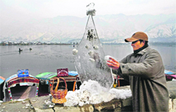 A boatman makes a sculpture out of an ice flake taken from the surface of the frozen Dal Lake in Srinagar