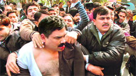 Securitymen take Delhi resident Kamran Siddiqui away after he threw black ink at Ramdev.