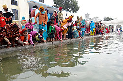 Devotees sprinkle holy water of the sarovar on themselves, at Gurdwara Haji Ratan on Maghi in Bathinda