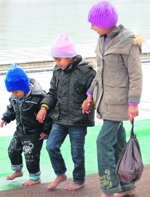 Children enjoy walking on a wet mat at the Golden Temple after a downpour lashed Amritsar on Sunday. 
