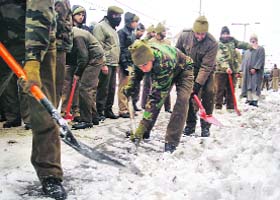 Army jawans remove snow from a road