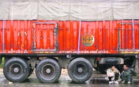 Truckers take shelter under a vehicle following rain on the Jammu-Srinagar national highway on Sunday