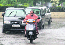 Commuters wade through water accumulated on a road after incessant rain. 