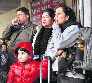 Travellers shiver at the bus stand due to intense cold in Jalandhar on Sunday.