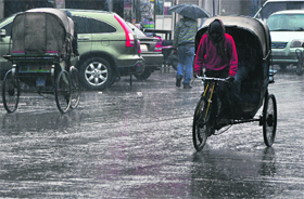 A rickahsw-puller caught in rain in Ludhiana on Sunday.