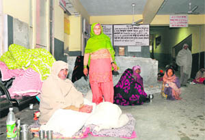 Owing to lack of proper arrangements, attendants of patients sit in an open corridor outside the maternity ward at the Karnal Civil Hospital in severe cold on Monday.