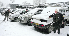 Drivers remove snow from their vehicles at a taxi stand in Srinagar on Monday.