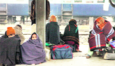 Passengers wrap themselves in blankets to stay warm at the railway station in Jalandhar on Monday.