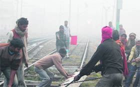 Employees work under freezing temperature and foggy weather near the railway station in Amritsar on Wednesday. 