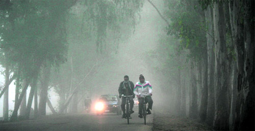 Commuters make their way through thick fog in Jammu on Wednesday. 