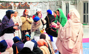 SGPC member Harjinder Kaur (second from left) campaigns for SAD candidate BS Ramoowalia at Amb Sahib Gurdwara in Mohali on Thursday as another supporter (encircled) distributes pamphlets