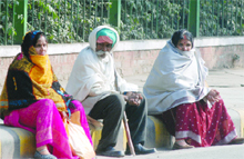 People face chilly wind as they waiting for the bus at a bus stand in New Delhi on Friday. 