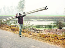 A worker carries water pipes in Lambi. 