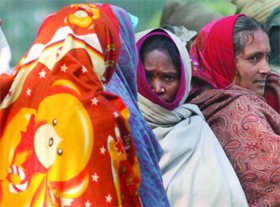 Women try to protect themselves from the cold wave in Delhi.