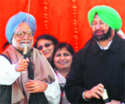 PM Manmohan Singh holds a sword presented to him by PPCC chief Amarinder Singh in Amritsar on Sunday.
