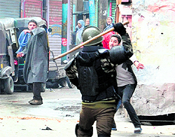 A policeman charges at a youth after activists of the Jammu and Kashmir Liberation Front clashed with security forces following a protest rally in Srinagar on Saturday
