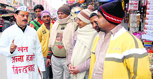 Rajesh Gaur clad in Annas attire generates awareness among customers and traders to not to cast their vote to a corrupt politician in Haridwar on Sunday.