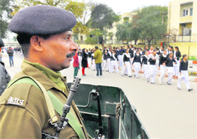 A policeman stands guard as schoolchildren emerge from the MA Stadium, Jammu, after a rehearsal for the Republic Day function on Sunday. 