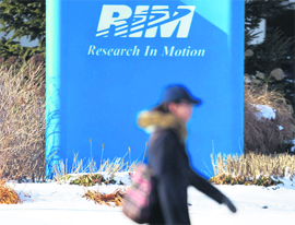 A pedestrian walks past a sign of Research in Motion at its headquarters in Waterloo, Ont. in Canada.