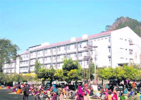 Patients and their attendants sit in a park outside the regional hospital in Chamba