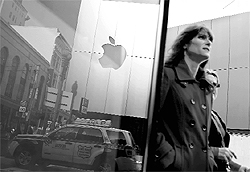 The Apple logo on an Apple Store is seen reflected in a window in San Francisco, Calif. Apple Inc's quarterly results on blew past Wall Street's expectations as US consumers snapped up near-record numbers of iPhones and iPads