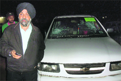 An official with a damaged vehicle of the election wing in Amb Sahib Colony, near Jagatpura, on Thursday night.