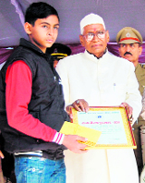 Governor Jagannath Pahadia honours a boy with a bravery award at the state-level Republic Day function in Ambala City on Thursday.