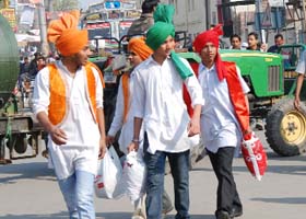 Youngsters, wearing colours of the Indian national flag, walk down a crowded market in Bathinda