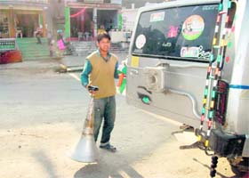 A supporter of a political party removes posters and banners from a vehicle in the Dhanaulti constituency near Mussoorie