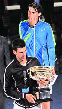 Novak Djokovic (L) receives the trophy after defeating Rafael Nadal on Sunday.