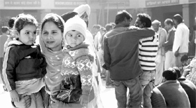 A mother carries her children to a polling booth at Fatehgarh Sahib on Monday.