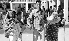 A boy holds hand of old women who came to the polling booth to cast their vote at the government school in Dera Bassi on Monday.