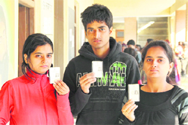 Siblings Nikhil, Amita and Richa show voter ID cards before casting their votes for the first time in Jalandhar on Monday.