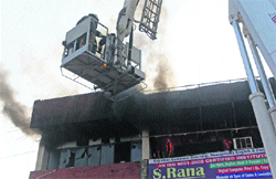 Firemen douse flames on the second floor of a showroom at Sector 41 in Chandigarh