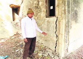 A worker shows a damaged portion of the Kushtha Ashram building in Rohtak