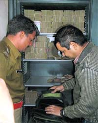 Policemen checking a bag with currency notes found in the safe at Ponty Chadhas office during a raid on Thursday
