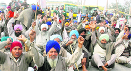Farmers block NH-1 to protest against a private agro-processing company in Amritsar on Friday.
